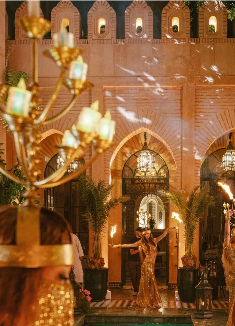 A performer raises a torch in a lantern-lit courtyard.