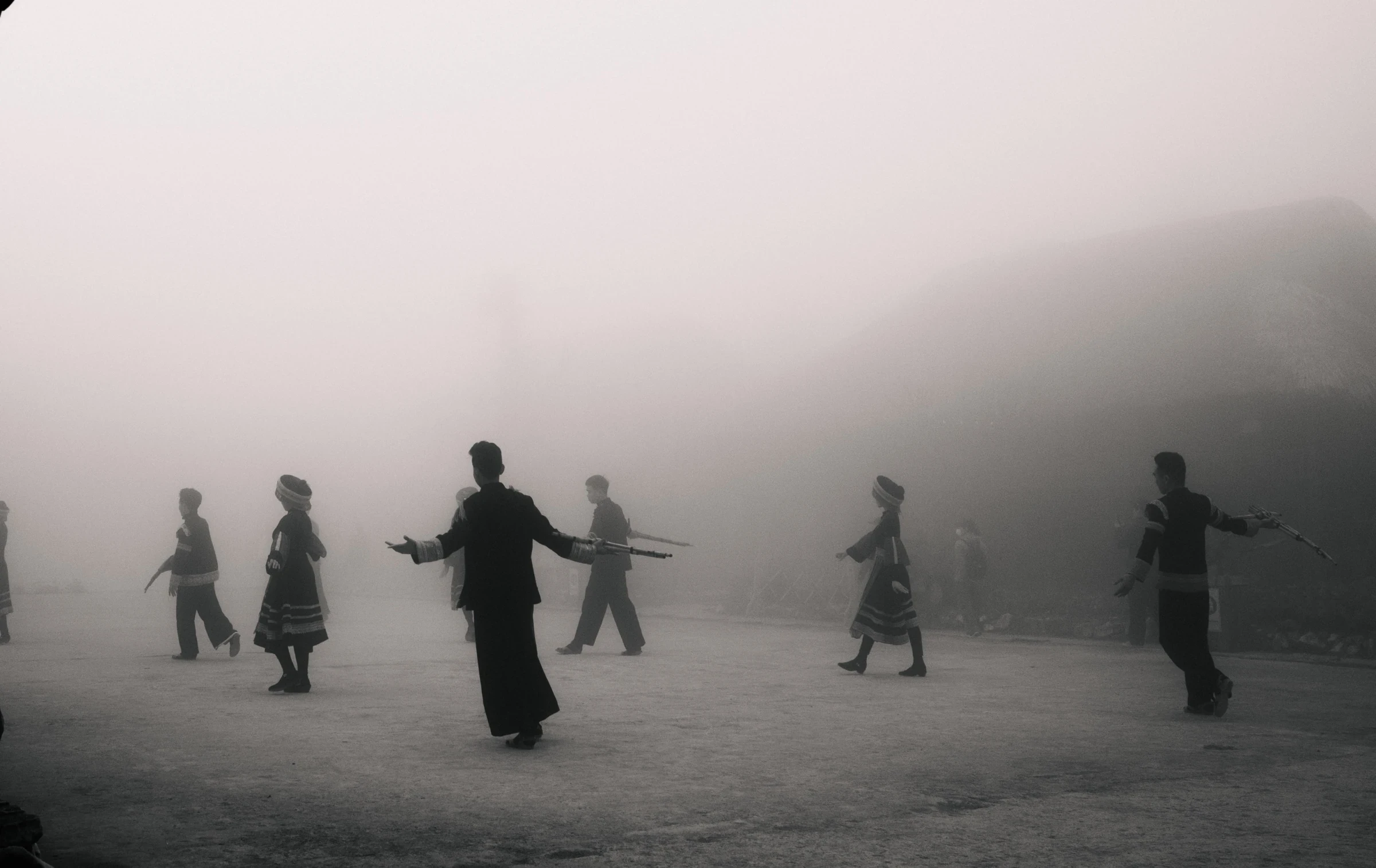 Figures moving through a mist-covered landscape